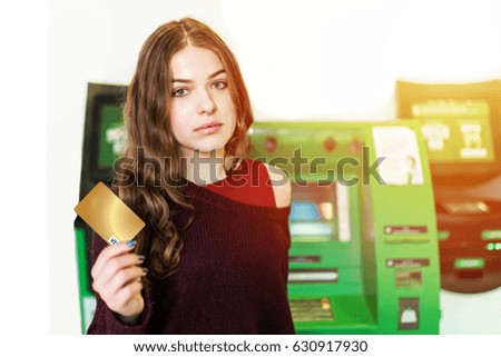 Girl stand near atm isolated on white background with gold card in the hands.