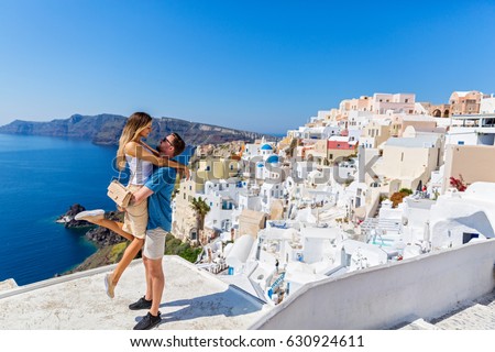 Young couple looks down on the landscape of the island of Santorini Royalty-Free Stock Photo #630924611