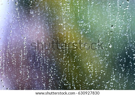 Raindrops flow down the glass on the street