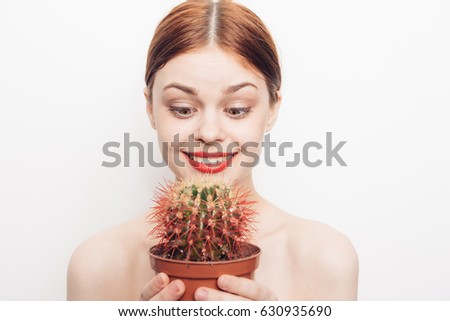 A woman joyfully stares at a cactus flower, a red cactus in her hands