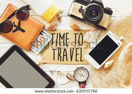 travel. time to travel concept text sign on card. summer planning vacation, flat lay. tablet, camera sunglasses compass passport money phone hat shells on white wooden background top view
