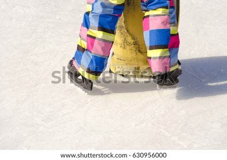 Closeup of legs in skates on ice rink, little girl take lessons