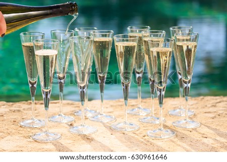 Many glasses of champagne or prosecco near resort pool in a luxury hotel. Pool party. Pouring drink into glasses. Horizontal
