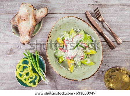 Fresh salad with cherry tomatoes, cucumber, sweet pepper and Parmesan cheese and glass of wine on wooden background. Healthy food. Top view