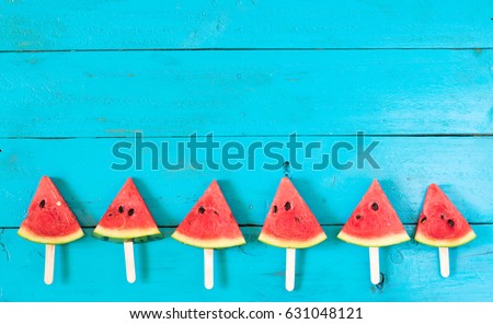 summer watermelon slice popsicles on a blue rustic wood background. copy space for designer
