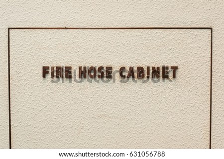 Fire hose cabinet sign on concrete background.