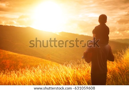 The boy sits on the shoulders of his father. Broga hill background .Golden hour scene . Royalty-Free Stock Photo #631059608