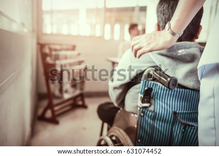 Nurse pushing wheelchair  with patient.. Young teen handicapped people sitting on wheelchair. Paralysis and impairment in real life. Royalty-Free Stock Photo #631074452