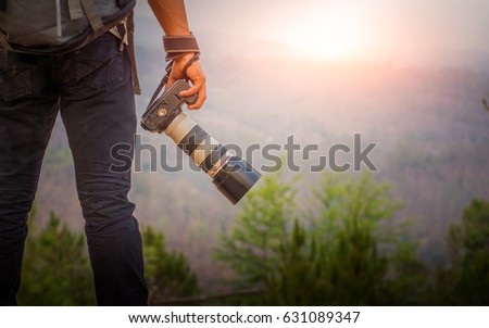 Young photographer holding his camera on mountain.