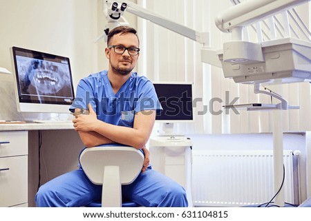 Handsome male dentist in a room with medical equipment on background.