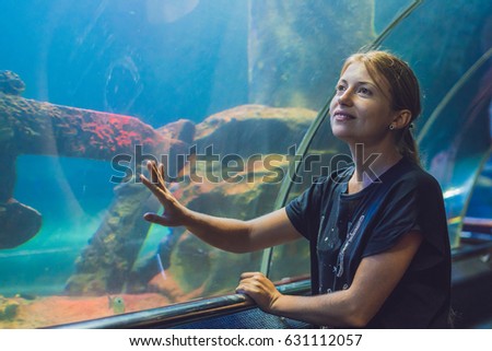 Young woman looking at fish in a tunnel aquarium.