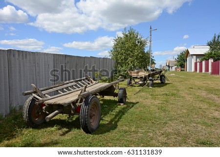 Carts without a horse stand in the village. A vehicle in the village of Vetkovsky district. Belarus. Gomel. The carts are at the fence. Country life. Country houses. Agriculture. Summer day. The sun