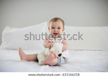 Cute baby girl playing with soft toy on bed in bedroom Royalty-Free Stock Photo #631166258