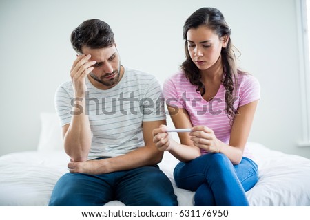 Worried couple finding out results of a pregnancy test in bedroom at home Royalty-Free Stock Photo #631176950
