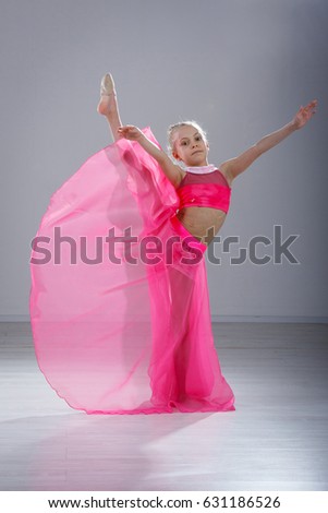 little girl gymnast in pink dress in the studio gray background