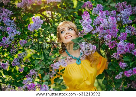 Beautiful girl in yellow dress posing near lilac