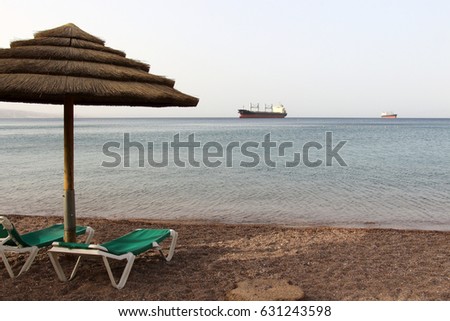 Morning on Eilat public beach. Large cargo Ship on horizon.