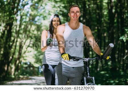 Young Beautiful Couple Riding Bike In Park
