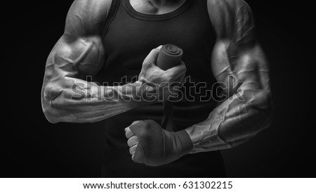 Strong hands and fist, ready for training and active exercise Close-up photo of strong man wrap hands Man is wrapping hands with boxing wraps isolated on black background 