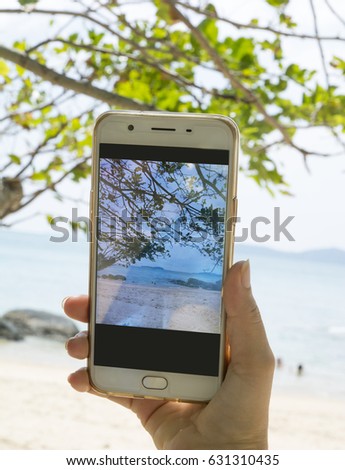 Women take a photo with mobile phone, take sea view on summer day, relax