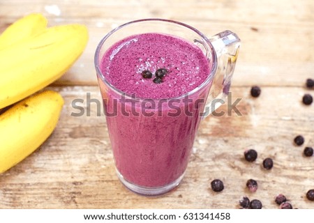 Healthy fresh smoothie drink from banana and blueberries in glass on wooden background, front horizontal view