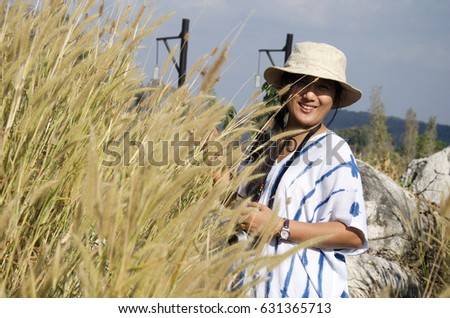 Thai women people travel and posing with stone and Poaceae or Gramineae at Suan Hin Pha Ngam or Thailand's Kunming for writing blog at Phu Luang Wildlife Sanctuary in Loei, Thailand
