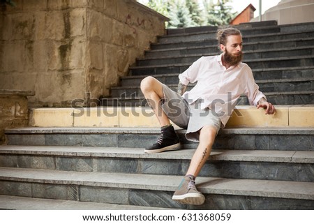 Fashion tattoed and bearded guy posing outdoor in the city