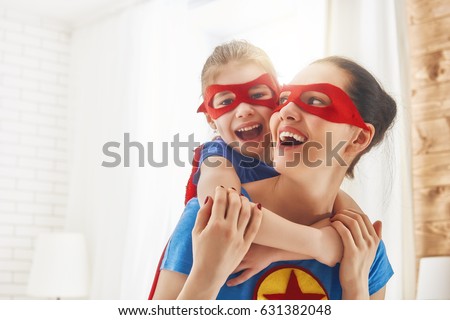 Mother and her child playing together. Girl and mom in Superhero costume. Mum and kid having fun, smiling and hugging. Family holiday and togetherness. Royalty-Free Stock Photo #631382048