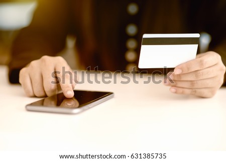 Woman using mobile phone to online shopping and pay by credit card. This picture is focus at woman's hand and use warm bright sunlight filter for feeling comfortable