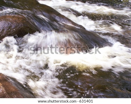 Stream water running over stones shot with slow shutter speed and in natural light.