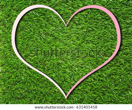 Creative pink heart paper frame on green grass background, love and nature concept