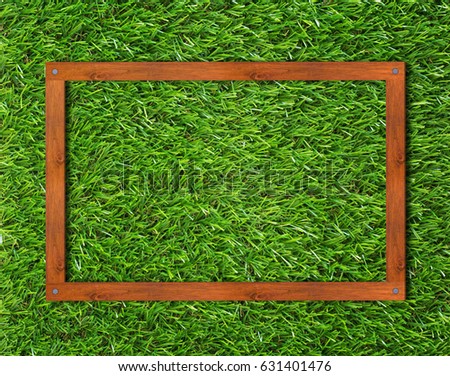 Creative wooden frame on green grass background, nature concept
