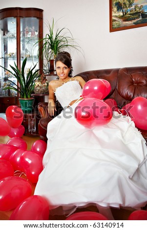Happy bride with red balls on sofa