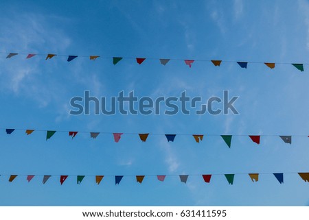 Colorful festive bunting flags against a blue sky background.
