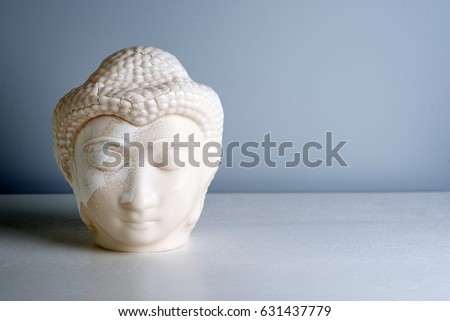 Buddha face. Buddha statue made of white marble with free space for text. Concept of peace, calm and tranquility. Buddhist artifact for Zen style interior decor.