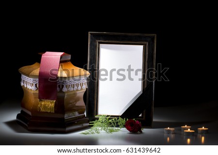 Wooden cemetery urn with blank mourning frame, red tape and candles