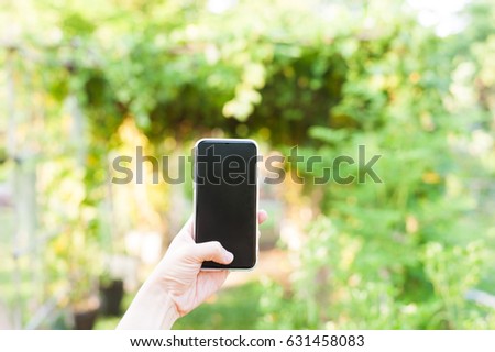 Woman using mobile-phone by left thumb in beautiful garden