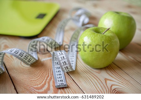 Healthy diet and diet for weight loss, scales, apples and tape measure on wooden background.