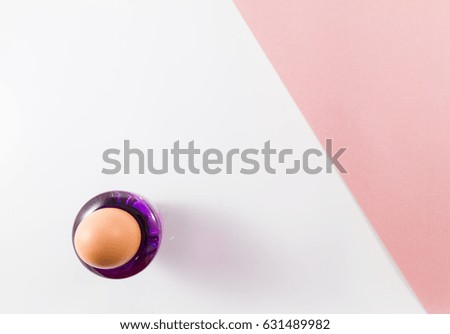 Top view of single egg on a white and diagonal pink background. Minimalist picture style with copy space for text