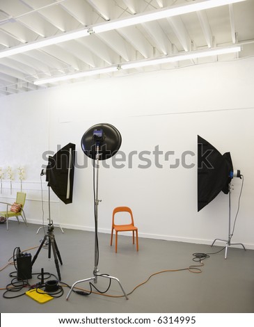 Studio shot of photographic lights aimed at red plastic chair.