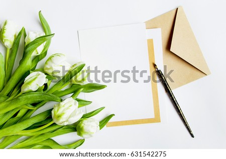 Letter, envelope and bunch of fresh tulips on white background. Vintage wedding invitation card or love letter with white flowers. Romantic or holiday concept, top view, flat lay, overhead view