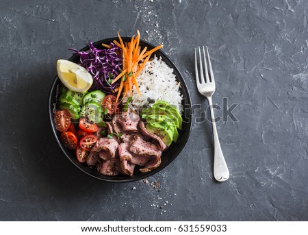 Beef steak, rice and vegetable power bowl. Healthy balanced food concept. On a dark background, top view    