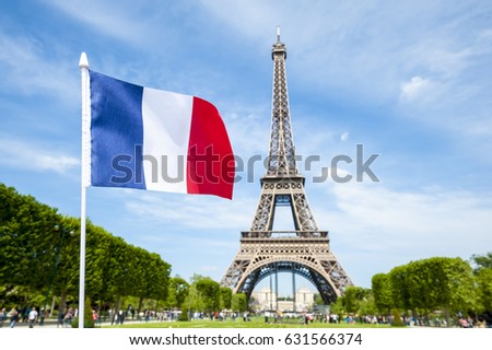 French flag flying in bright blue spring sky in front of the Eiffel Tower in Paris, France Royalty-Free Stock Photo #631566374