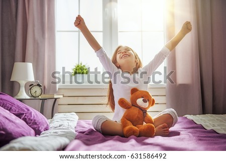 A nice child girl enjoys sunny morning. Good time at home. Kid wakes up from sleep. Royalty-Free Stock Photo #631586492