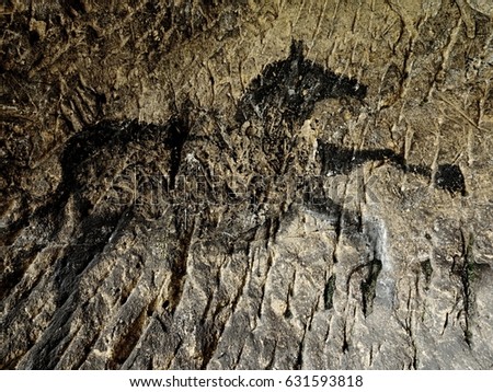 Black carbon horses on sandstone wall. Paint of hunting,  prehistoric picture. Discovery of prehistoric paint of horse in sandstone cave. Spotlight shines on historical human painting. 