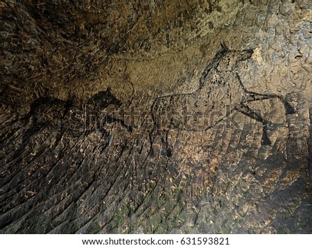 Black carbon horses on sandstone wall. Paint of hunting,  prehistoric picture. Discovery of prehistoric paint of horse in sandstone cave. Spotlight shines on historical human painting. 