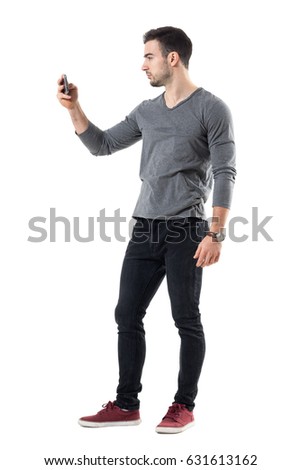 Side view of cool relaxed young casual man taking picture with mobile phone. Full body length portrait isolated over white studio background.