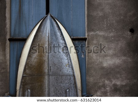 Metal hull with rivets of a boat stored vertically against the wall