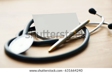 Medical business card with stethoscope and pen on the table.