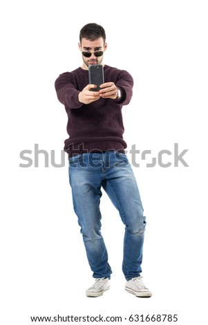 Casual young tourist taking picture with cellphone aiming at camera. Full body length portrait isolated over white studio background.